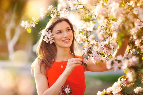 Vacker ung flicka i parken och en blommande träd — Stockfoto