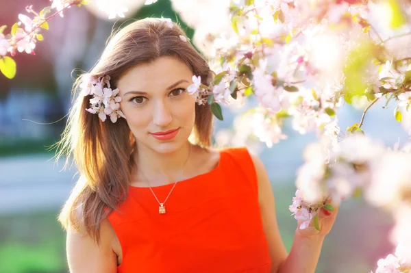 Beautiful young woman in spring garden near blooming tree — Stock Photo, Image