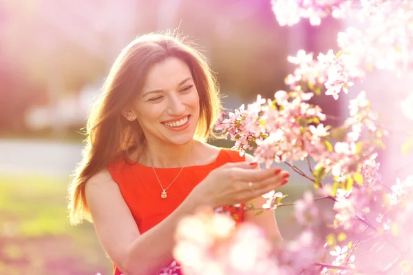 Schöne junge Frau im Frühlingsgarten in der Nähe blühender Bäume — Stockfoto