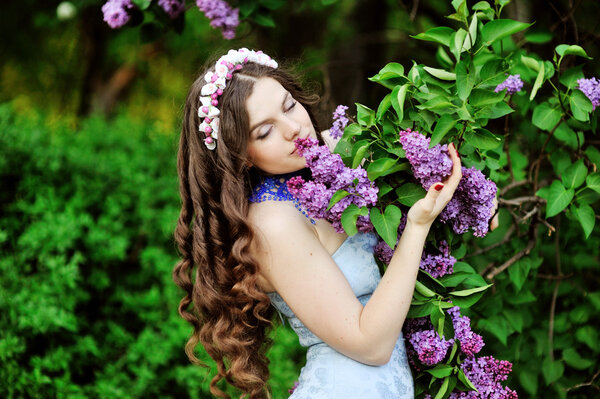 Portrait of young woman near the blossoming lilac
