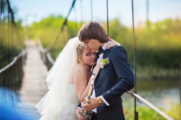 Unga lyckliga bruden och brudgummen står på en bro medan bruden pekar på copyspace — Stockfoto