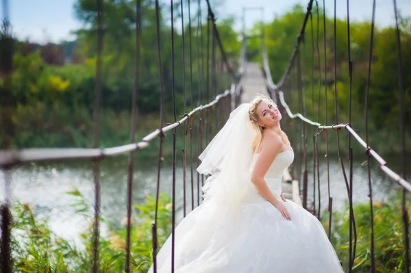 Young beautiful bride is standing on the bridge — Stock Photo, Image