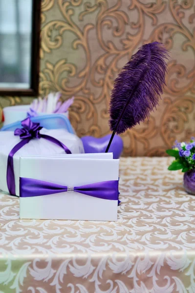 Beautiful wedding envelope with a purple ribbon and pen on the table — Stock Photo, Image