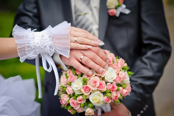 Mãos da noiva e noivo com anéis em buquê de casamento — Fotografia de Stock