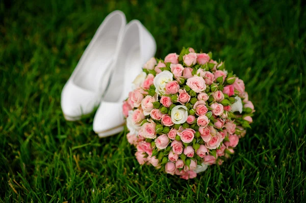 Bouquet da sposa e scarpe bianche femminili sull'erba — Foto Stock