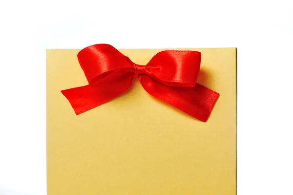 Festive gold box with a red bow on a white background — Stock Photo, Image