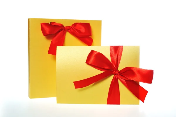 Святкова золота коробка з червоним бантом на білому тлі — стокове фото