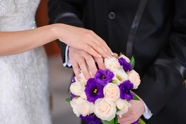 Mains du marié et de la mariée sur le bouquet de mariage — Photo