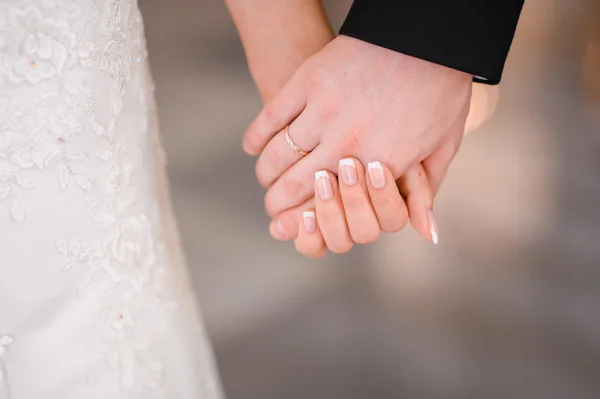 Bride and groom holding hands outdoors — Stock Photo, Image