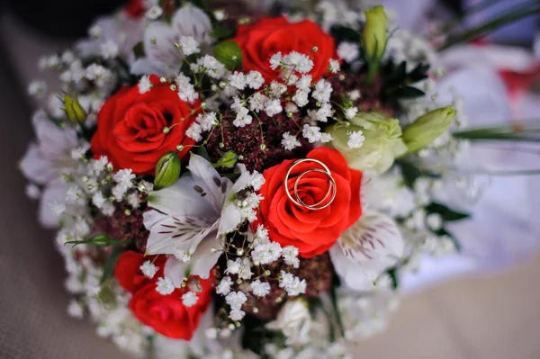 Zlaté snubní prsteny na kytici růží — Stock fotografie