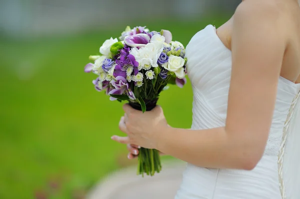 Bröllop bukett i händerna på bruden i profil lila blommor — Stockfoto