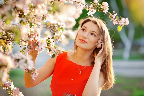 Beautiful young girl on a background of flowering trees — Stock Photo, Image