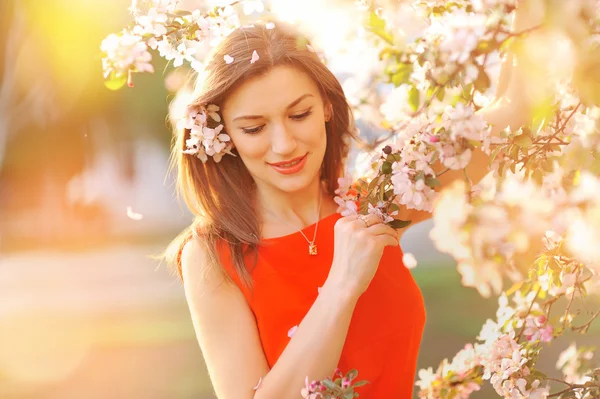 Vacker ung flicka på en bakgrund av blommande träd — Stockfoto