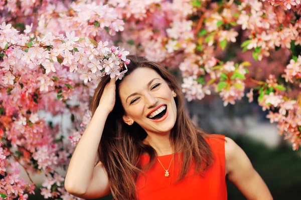 Schöne junge Mädchen auf einem Hintergrund von blühenden Bäumen — Stockfoto