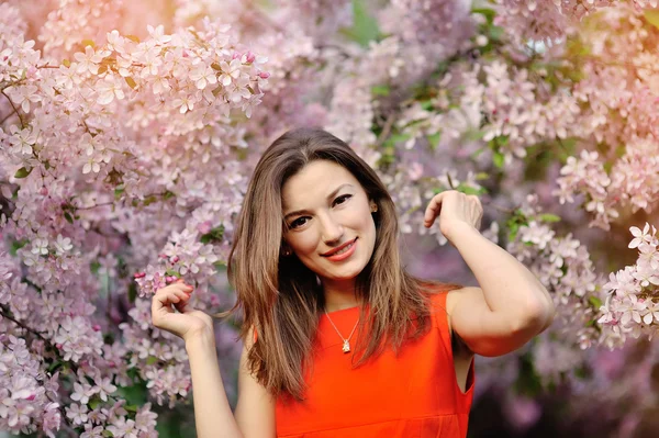 Menina bonita em vestido vermelho e árvores floridas — Fotografia de Stock