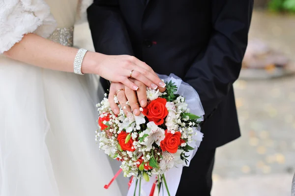 Mani degli sposi con anelli su un bellissimo bouquet da sposa — Foto Stock