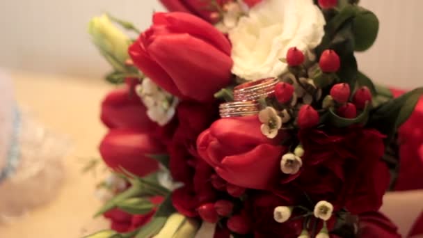 Νυφικό μπουκέτο με κόκκινα τριαντάφυλλα και δαχτυλίδια πάνω στο τραπέζι — Αρχείο Βίντεο