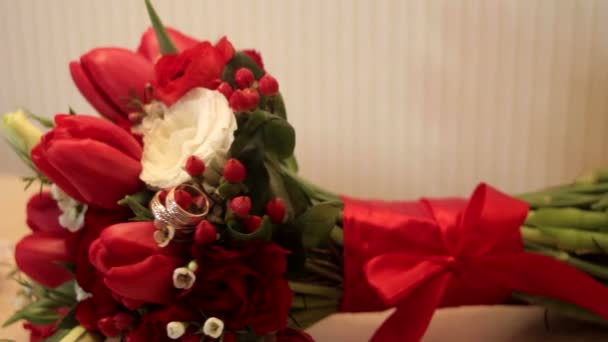 Buquê nupcial de rosas vermelhas e anéis na mesa — Vídeo de Stock