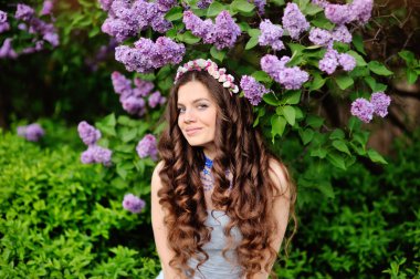 Beautiful young woman in lilac flowers, outdoors portrait