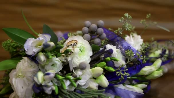 Gold rings lie on a beautiful bride's bouquet — Stock Video