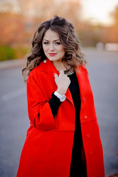 Piękna dziewczyna w czerwonym płaszczu stojący na drodze — Zdjęcie stockowe