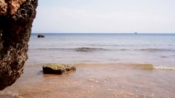Пляж с волнами и большим камнем — стоковое видео
