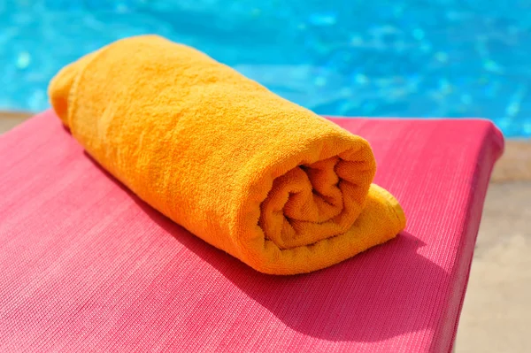 Toalha laranja dobrada no fundo da piscina — Fotografia de Stock