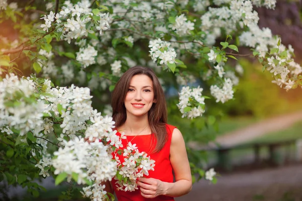 Vacker flicka står nära ett blommande träd — Stockfoto