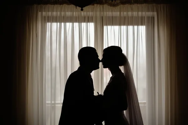 Silhouettes of the bride and groom on the background of a window — Stock Photo, Image