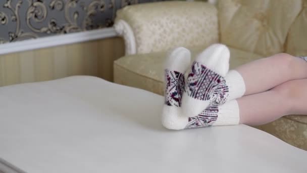 Patas femeninas en bonitos calcetines de punto sobre la mesa — Vídeo de stock