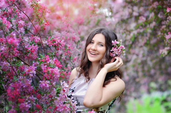 Beautiful smiling brunette in the flowered garden — Stock Photo, Image