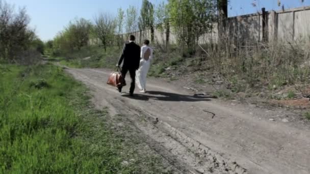 Braut und Bräutigam gehen den Weg entlang — Stockvideo