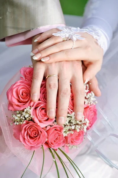 Hand the bride and groom with the rings lying on the bridal bouquet — Stock Photo, Image