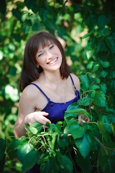 Mooi meisje op een achtergrond van groene bladeren in zomer park — Stockfoto