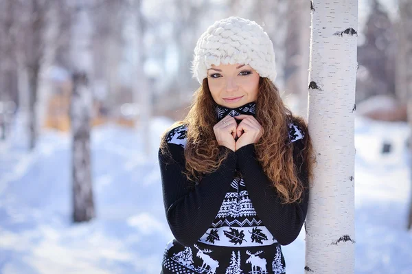 Beautiful girl in white hat stands near the birch in winter — Stock Photo, Image