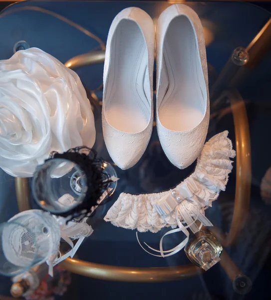 Белые свадебные туфли и другие свадебные атрибуты на столе — стоковое фото