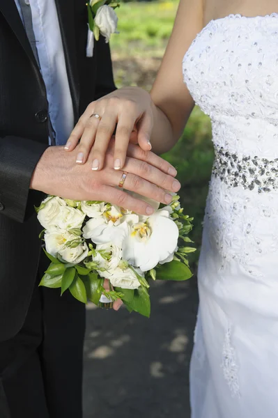 Hand bruden och brudgummen med ringar på bröllop bukett — Stockfoto