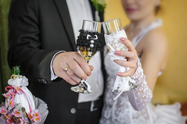 Beautiful decorated wedding glasses in the hands of the bride an — Stock Photo, Image