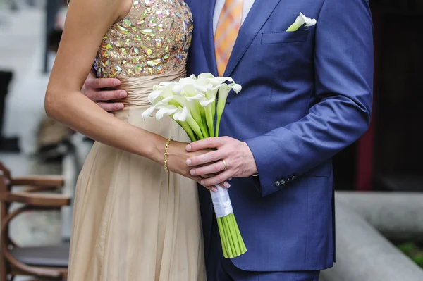 Bruden och brudgummen håller en bröllop bukett av callas — Stockfoto