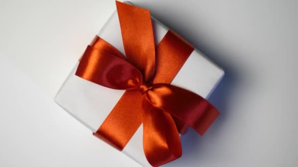Coffret cadeau blanc avec ruban rouge sur fond blanc avec place pour votre texte. Motion vidéo le jour de la Saint-Valentin, fête des mères ou anniversaire. Vidéo 4k vue de dessus — Video