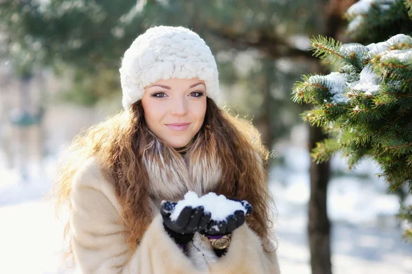 Jeune femme en chapeau et mitaines riant en jouant avec la neige en plein air — Photo