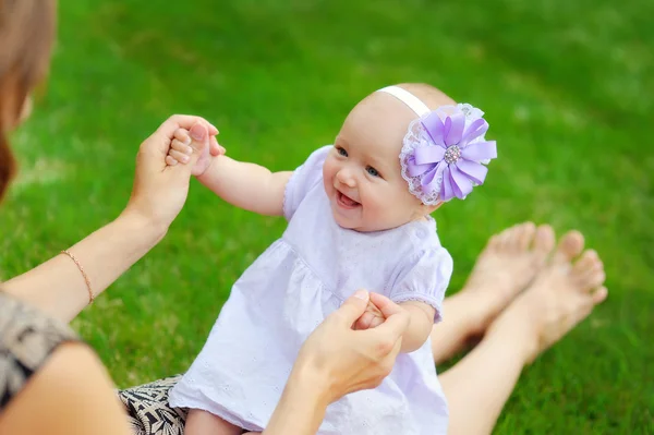 Beautiful happy little baby girl sitting on a green meadow  dand — Stock Photo, Image