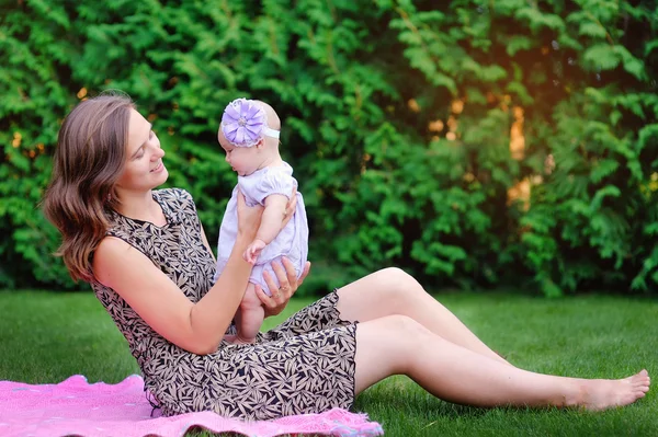 Mamma håller i händerna på en liten dotter utomhus i parken — Stockfoto