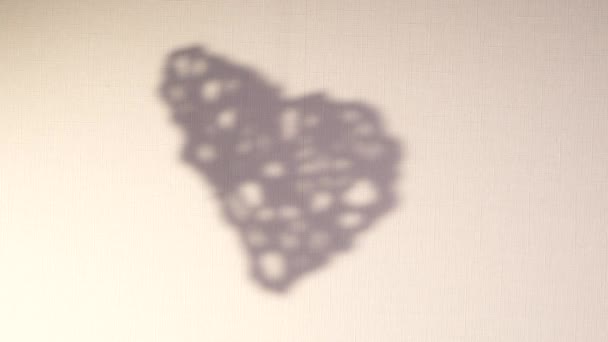 Silhouette astratta ruotare sfondo ombra del cuore che cade sulla parete. Ombra sfocata trasparente di giocattolo di San Valentino con posto per testo. Video 4k per sovrapposizione su sfondo e mockup — Video Stock