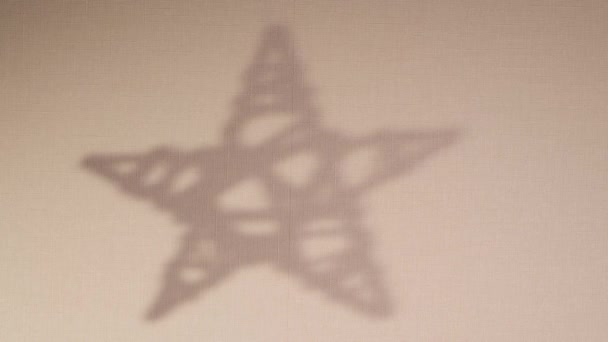 La silueta abstracta rota el fondo de sombra de la estrella que cae en la pared. Sombra borrosa transparente del juguete de Navidad con lugar para el texto. Imágenes de vídeo 4k para superposición en el fondo y maqueta — Vídeo de stock