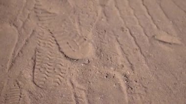 Kumda ayak izleri, parlak, güneşli bir günde, büyük kumlar manzarayı eğip büker. Metin için yer alan 4k video hareketi görüntüsü