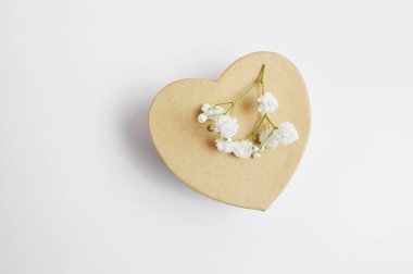 Kalp şeklinde el işi bahar hediyesi kutusu ve beyaz arka planda izole edilmiş beyaz çiçekler, sevgililer günü mesajınız için yer var.