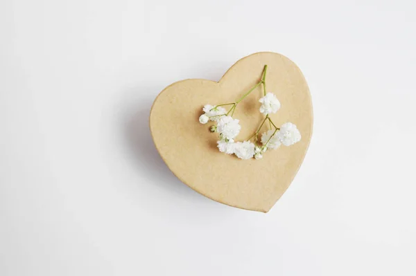 ハート型のクラフト春のギフトボックスと白い背景に隔離された白い花、あなたのバレンタインテキストのための場所 — ストック写真