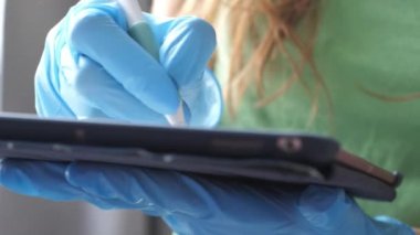 Eldivenli doktor tablet tutuyor ve beyaz kalemle yazıyor.