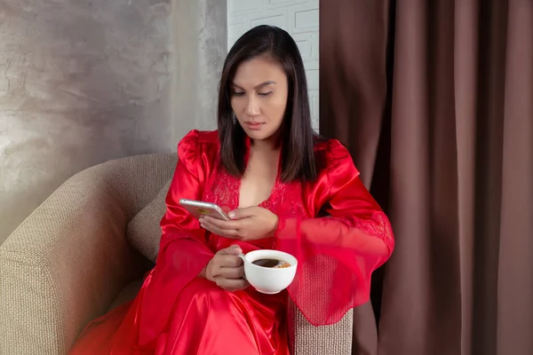 Mulher Camisola Vermelha Segurando Uma Xícara Cacau Olhando Para Smartphone — Fotografia de Stock